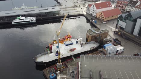 Norled-ferry-Sveio-and-Amundsen-diving-vessel-Basen-alongside-in-Stavanger-city-Norway---Descending-aerial-with-tilt-up