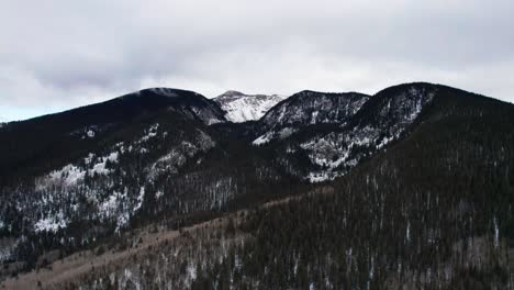 Drone-shot-pulling-back-away-from-a-high-elevation-snow-covered-mountain