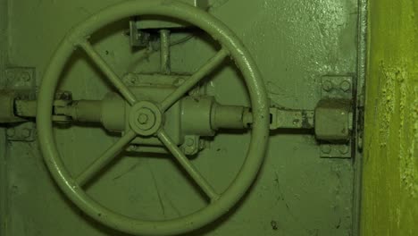 Steel-door-lock-inside-the-concrete-bomb-shelter-to-hide-civil-people,-an-underground-apocalypse-bunker-built-in-old-coastal-fortification,-medium-handheld-closeup-dolly-shot-moving-left