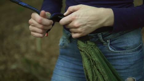 Footage-of-a-women-clipping-in-a-carabiner-so-she-can-fix-a-hammok-between-to-trees-in-the-forest-in-germany