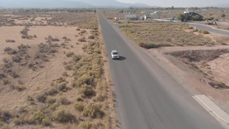 Car-driving-forwards-through-small-town-drone-shot