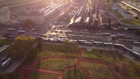 Aerial-birds-eye-shot-of-park-in-front-of-Retiro-Train-Station-and-bus-traffic-for-passenger-transport-during-sunset---Buenos-Aires-City,Argentina