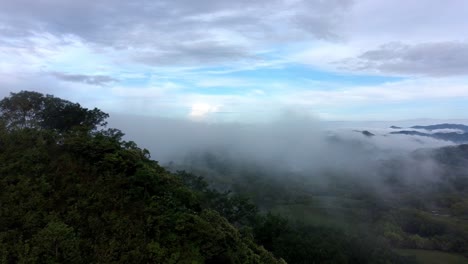 Drone-flying-over-jungle-hill-in-misty-cloudscape