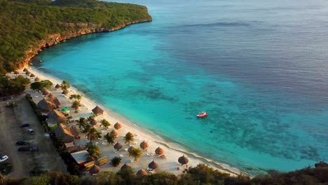 Aerial-dolly-out-view-of-Cas-Abao-Beach-with-a-boat-on-the-shore-on-the-Dutch-island-of-Curacao-at-sunset,-caribbean-sea