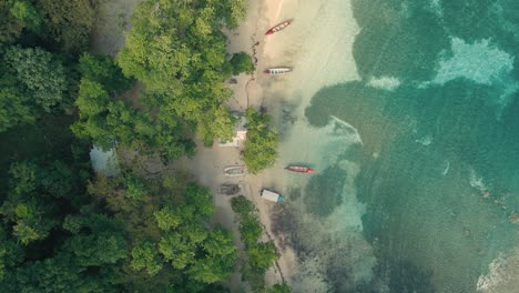 Drone-shot-of-beach-and-blue-clear-water-with-a-fisherman's-boat