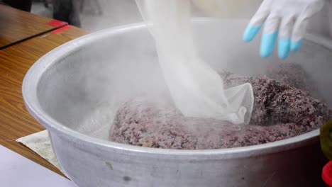 Fresh-bag-of-steaming-hot-purple-rice-tipped-into-large-silver-bowl