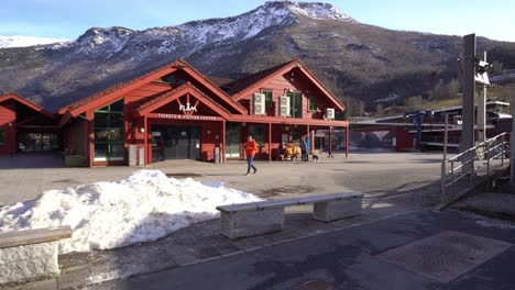 Walking-towards-Flam-tourist-office-and-ticket-center-in-beautiful-sunny-spring-morning---Wide-angle-overview-with-mountain-background
