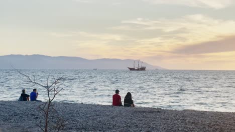 Paare-Sitzen-Am-Strand-In-Mexiko-Und-Beobachten-Boote-Bei-Sonnenuntergang