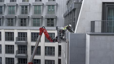 Construction-Worker-Working-on-Building's-Fascade-from-Cherry-Picker