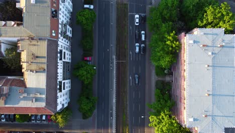 Camera-tracks-cars-Traffic,-wait-at-an-intersection-and-drive-off-Smooth-aerial-view-flight-Drone-top-down-view
of-Berlin-Prenzlauer-Berg-Allee-Summer-2022