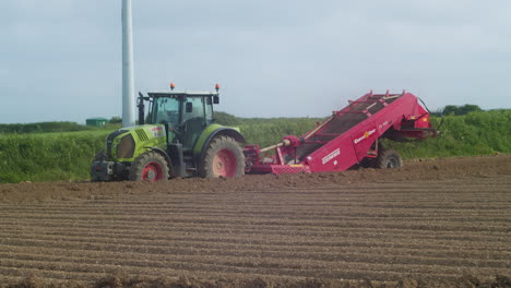 Farmer-Driving-Tractor-Ploughing-Soil-in-a-Field-on-a-Summers-Day-in-Cornwall,-England---Telephoto-shot