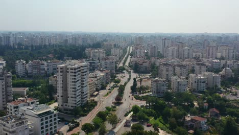 aerial-drone-passing-a-highway-road-in-the-center-of-Antalya-Turkey-along-the-coast-of-the-Mediterranean-Sea-on-a-sunny-summer-day-surrounded-by-tall-residential-apartment-buildings