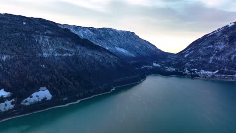 Drone-Aerial-view-of-mountains-with-snow-in-winter,-lake-and-blue-hour-in-the-morning