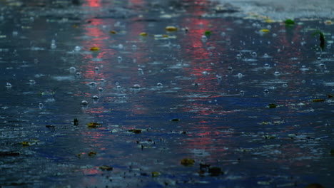 Slow-motion-of-raindrops-falling-on-submerged-road-in-rainy-season