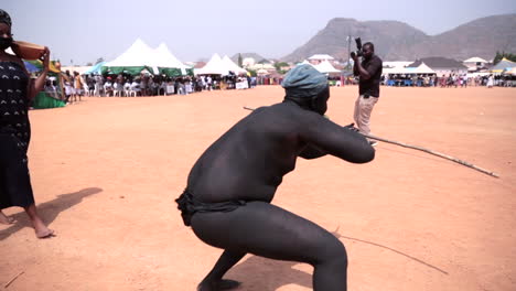 Hombre-Gbagyi-Nigeriano-En-Negro-Oscuro-Hace-Una-Danza-Tradicional-De-Caza-En-Un-Festival-Nacional-Del-Cuerpo-De-Servicio-Juvenil