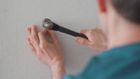 Man-installing-a-picture-hanging-hook-on-the-wall