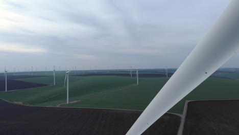 Wind-Turbine-Farm,-Distant-Aerial-Drone-View-with-Blade-Crossing-Frame