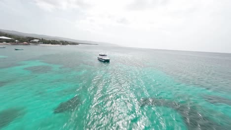 Aerial-drone-fpv-flying-over-moored-boats-in-turquoise-sea-waters-of-Playa-Ensenada-beach,-Dominican-Republic