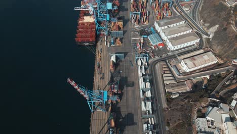 Aerial-dolly-in-of-a-container-cargo-ship-docked-near-cranes-in-Valparaiso-Sea-Port-ready-to-be-loaded,-Chile