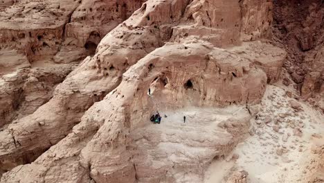 Group-of-tourists-listen-to-a-guide-at-The-Arches-in-the-dry-Timna-Park-in-the-red-canyon-in-the-Negev-Desert-in-southern-Israel