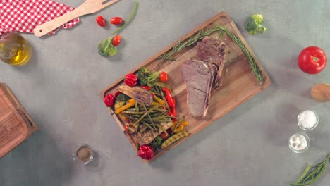 A-top-view-of-steak-with-vegetable-salad-on-a-wooden-plate