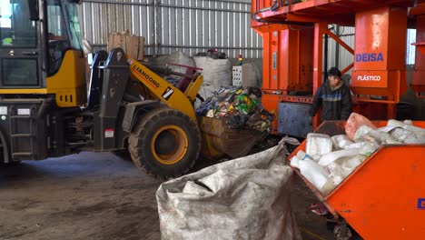 A-bulldozer-loaded-with-compacted-garbage-moves-away-inside-a-waste-processing-plant