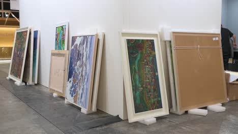 During-the-setup-and-installation-day,-art-paintings-are-seen-on-the-ground-waiting-to-be-hung-for-sale-prior-to-the-opening-of-a-contemporary-art-fair