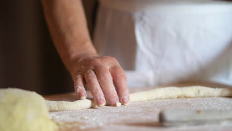 Mother-at-home-rolling-fresh-dough-for-italian-gnocchi-with