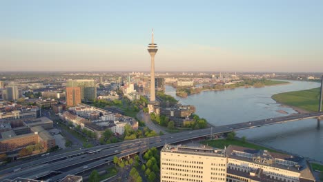 Rhine-tower-and-morning-traffic-crossing-Rhine-bridge-in-Dusseldorf,-Drone-aerial-shot