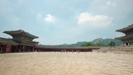 Tourist-people-walking-from-Geunjeongmun-gate-to-Gyeongbokgung-Palace-in-Seoul,-wide-shot-side-view