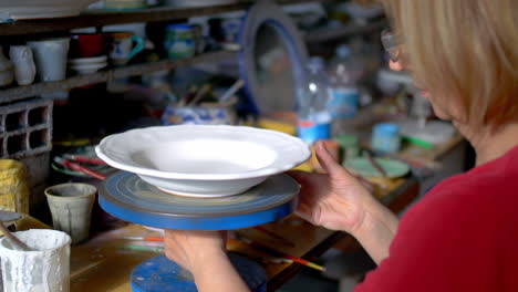 Italian-woman-puts-plate-on-turntable-in-a-craft-workshop