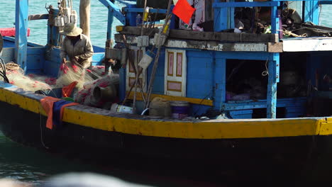 Fisherman-working-on-Vietnamese-fishing-boat-floating-on-ocean-harbor