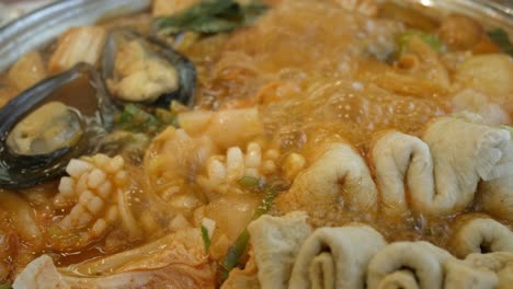 Nahaufnahme-Der-Kochenden-Koreanischen-Kimchi-Tteok-Pokki-Suppe-Voller-Schweinefleisch,-Tintenfisch,-Muscheln,-Ehmook-Fischplatte-Und-Gemüse