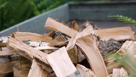 Pieces-of-birch-wood-are-thrown-onto-pile-of-firewood,-close-slomo-pan