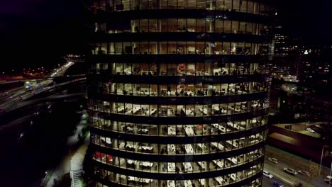 Aerial-view-boom-down-of-an-office-building-with-people-working-late-at-night,-Titanium-Park,-Santiago,-Chile