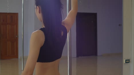 Latina-pole-dancer-walking-around-the-pole-while-looking-at-herself-in-the-mirror-in-the-background