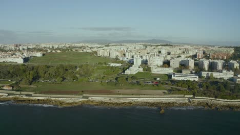 Aerial-close-up-view-of-the-marginal-with-ocean-and-traffic-on-the-coast-in-sunny-day,-Oeiras,-Portugal