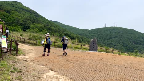 Toma-En-Cámara-Lenta-De-Una-Pareja-De-Excursionistas-Con-Mochila-Escalando-En-Las-Montañas-Surcoreanas-En-El-Parque-Nacional-Jirisan-Durante-El-Día-Soleado