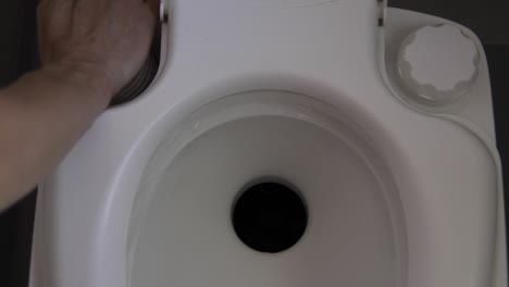 Frau-Spült-Leere-Herausnehmbare-Wohnmobiltoilette,-Indem-Sie-Den-Knopf-Drückt-Und-Druck-Erzeugt,-Damit-Wasser-Die-Toilette-Spült