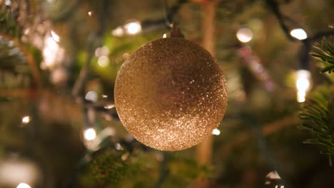 gold-ornament-ball-on-Christmas-tree-with-bokeh-lights-in-4k