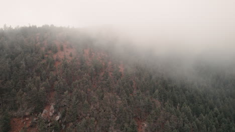 Aerial-rise-through-mist-and-fog-over-peak-above-Cheyenne-Canyon,-Colorado