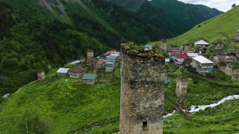 Luftaufnahme-Der-Alten-Turmruine-Im-Dorf-Adishi-Mit-Den-Kaukasusbergen-Der-Region-Swanetien-In-Georgien