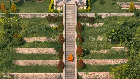 Frau-Im-Orangefarbenen-Chiffonkleid-Rennt-Steile-Stufen-Im-Ujung-Park,-Bali-Tempel,-Hinauf
