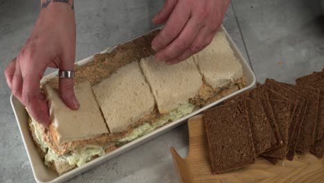 White-bread-slices-added-to-Smorgastarta,-slices-of-rye-sit-nearby