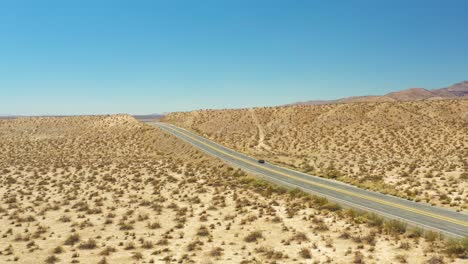 Descending-aerial-view-of-Midland-Trail's-Highway-14-through-the-Mojave-Desert-landscape