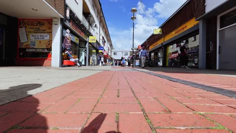 Low-angle-ground-surface-pov-of-Crawley-city-center-in-UK-with-people-walking-downtown,-Fpv-moving-forward