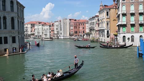 Gondeln-Transportieren-Touristen,-Die-An-Einem-Schönen-Sommertag-Am-Canal-Grande-In-Venedig-Vorbeifahren