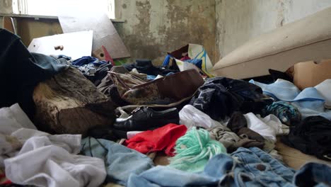 Close-slowmotion-shot-in-abandoned-house-in-a-lonely-village-full-of-old-clothes-and-trash
