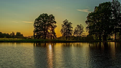 Ruhiger-Sonnenuntergang-Am-See-Mit-Reflexionen-Einer-Silhouette-Von-Bäumen