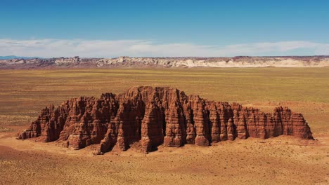 Massive-red-rock-formation-towering-in-the-middle-of-dead-wild-west-desert-in-Utah,-United-States-of-America---aerial-dolly-pull-back